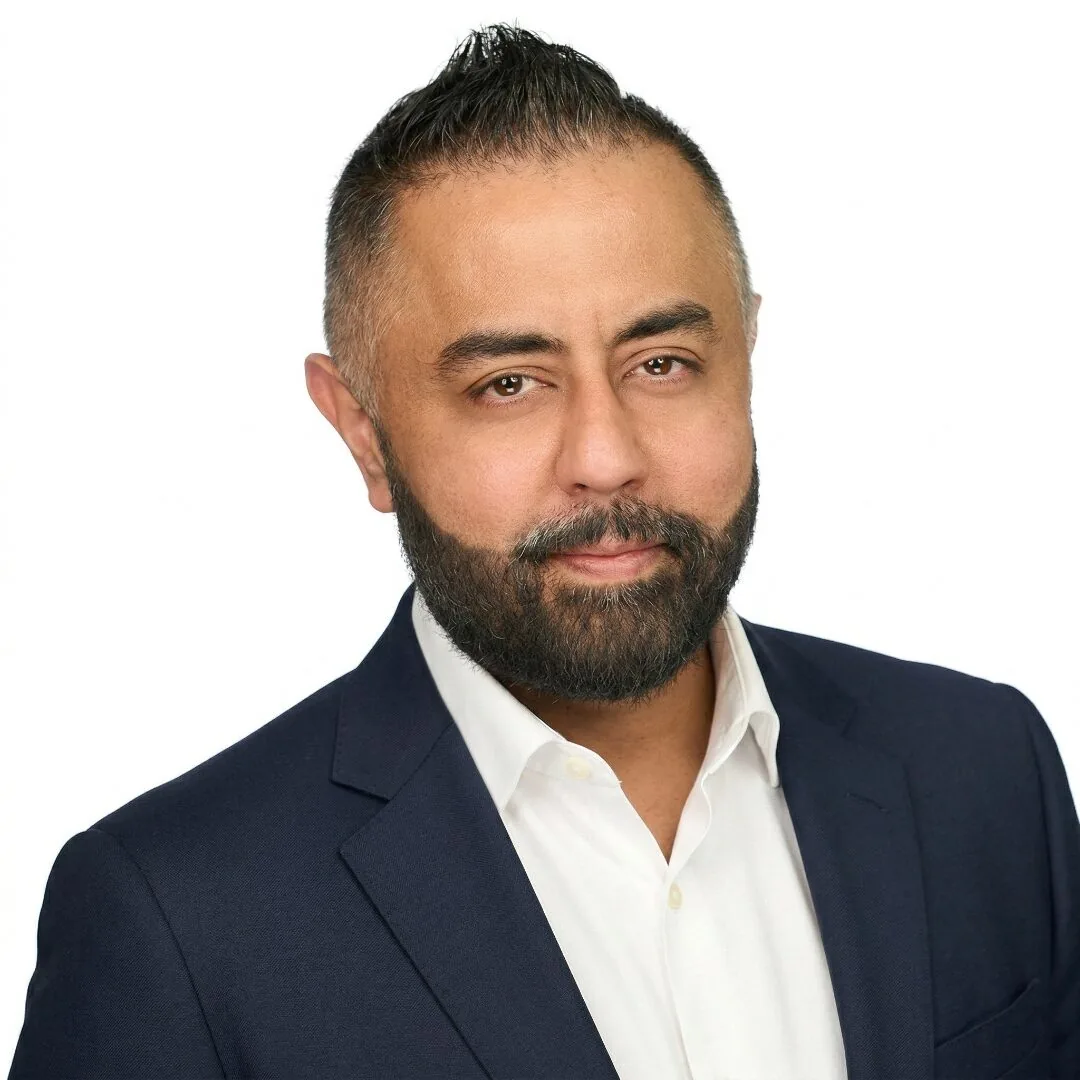 Omer Qureshi headshot — navy suit studio portrait