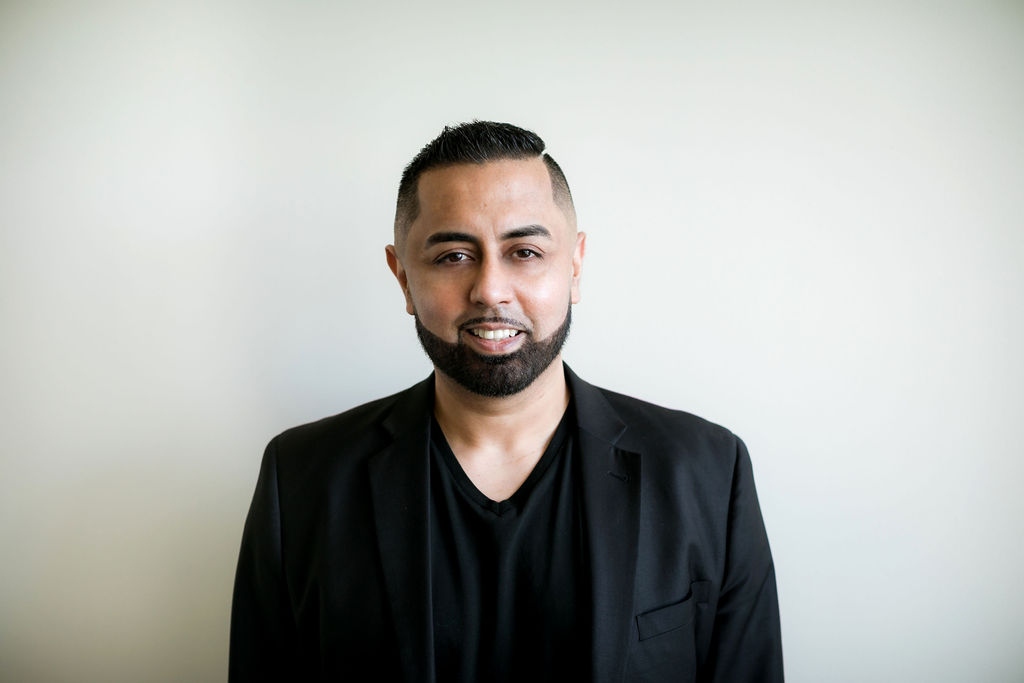 Omer Qureshi in a black blazer, studio portrait.