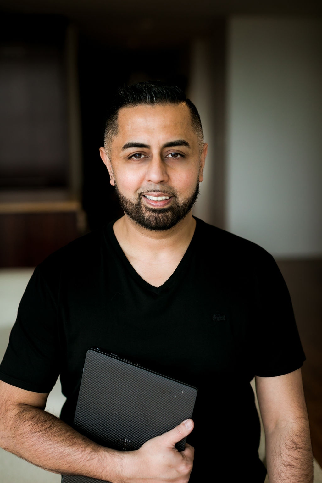 Omer Qureshi holding a tablet in a relaxed portrait.