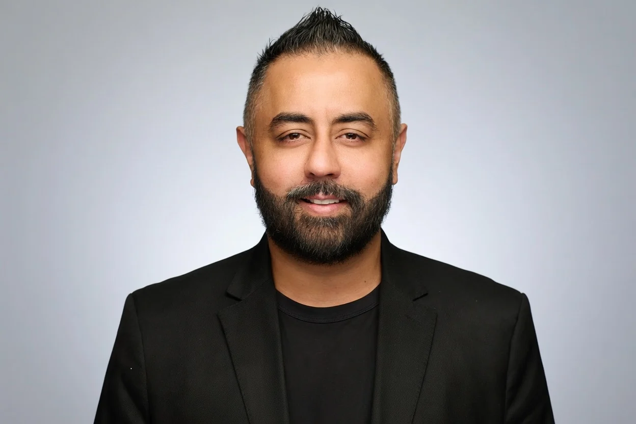 Omer Qureshi in a black jacket, studio portrait.