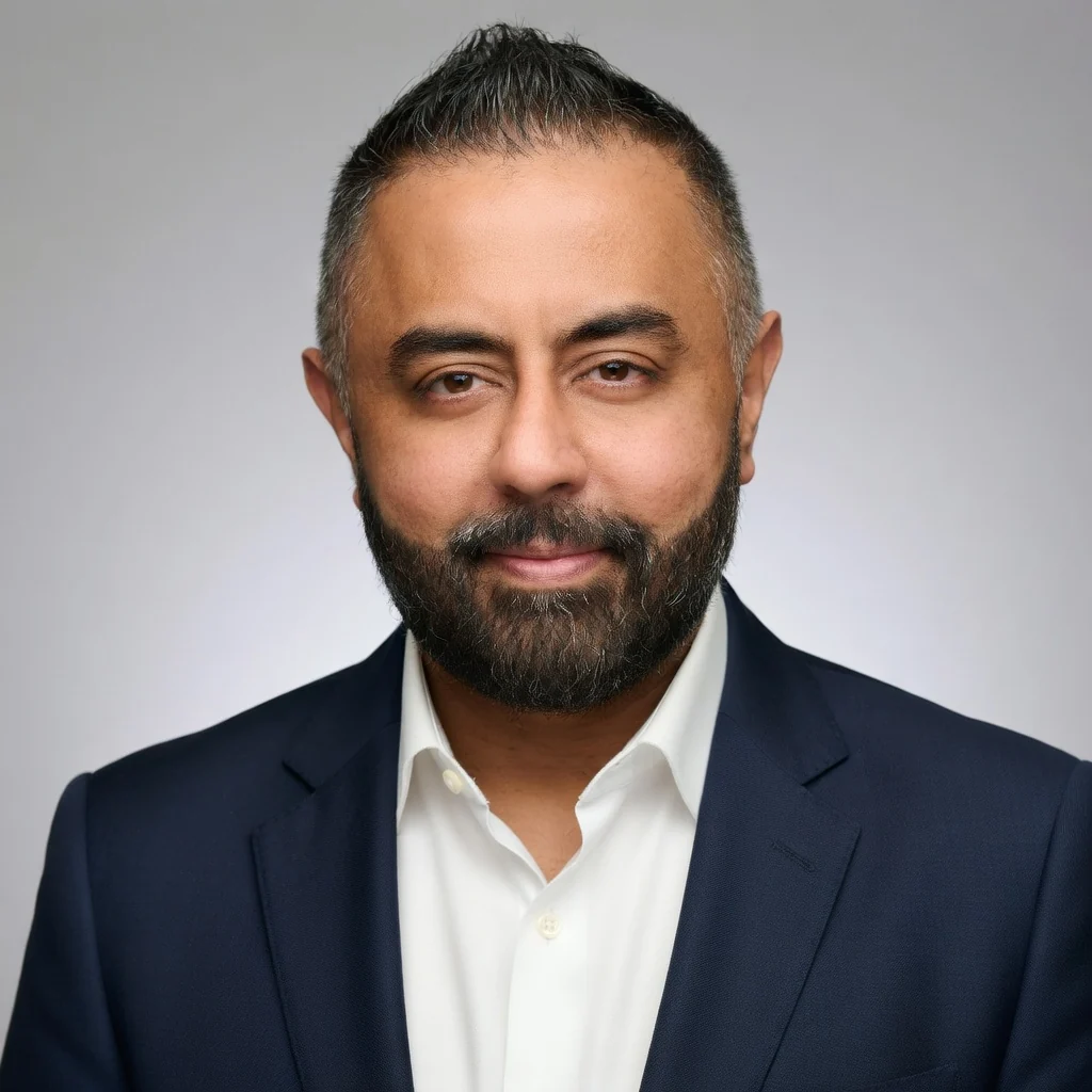 Omer Qureshi headshot — navy suit studio portrait